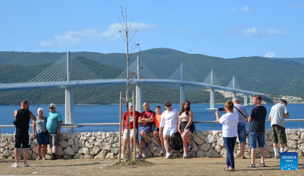 People take souvenir photos in front of the Peljesac Bridge in Komarna, Croatia, on Aug. 29, 2023. The Peljesac Bridge in the south of Croatia, built by a Chinese consortium led by the China Road and Bridge Corporation (CRBC), connects the Croatian mainland with the Peljesac peninsula, giving the country a continuous land link that bypasses Bosnian territory(Photo: Xinhua)