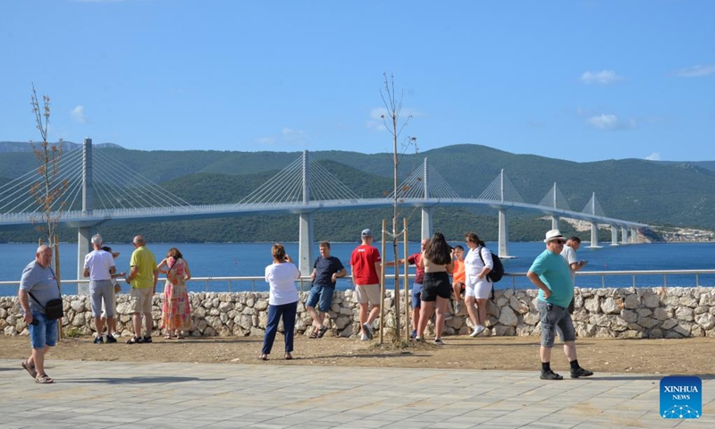 People take souvenir photos in front of the Peljesac Bridge in Komarna, Croatia, on Aug. 29, 2023. The Peljesac Bridge in the south of Croatia, built by a Chinese consortium led by the China Road and Bridge Corporation (CRBC), connects the Croatian mainland with the Peljesac peninsula, giving the country a continuous land link that bypasses Bosnian territory.(Photo: Xinhua)