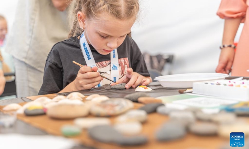 A girl paints on a stone during a Knowledge Day event to celebrate the start of the new school year on the central square of Vladivostok, Russia, Sept. 2, 2023. Programs like popular sciences, painting, dictation, handicraft, fire safety knowledge and other activities on Knowledge Day attracted many children. Photo: Xinhua