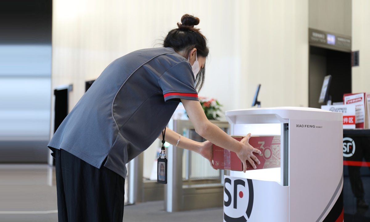 An SF Express employee puts a parcel into a machine that can weigh and measure the parcel simultaneously at the CIFTIS. Photo: Courtesy of SF Express