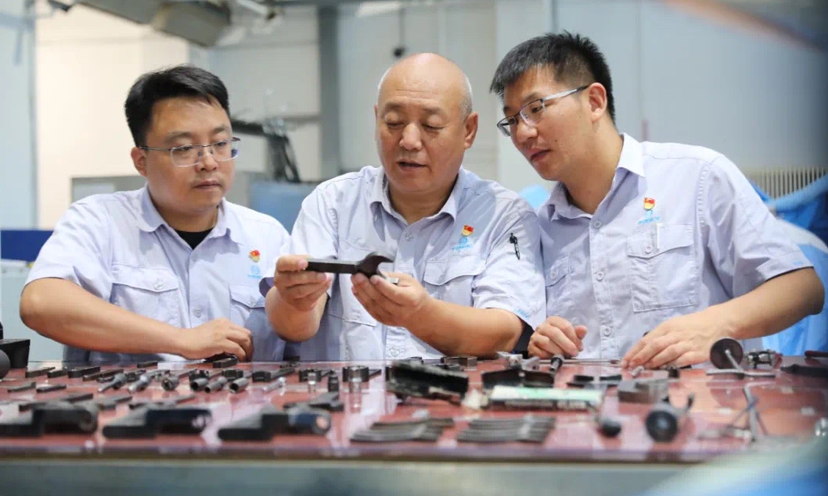 Li Zhiqiang (center) and his colleagues examine tools in a workshop. Photo: Courtesy of the Aero Engine Corporation of China
