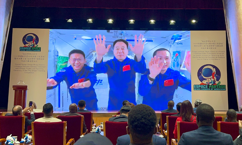 The Shenzhou-16 crew wave their hands as they extend greetings to the award-winners of a painting competition, which involved around 2,000 African young artists. Behind them are the selected paintings they took to space in May. Photo: Fan Anqi/ GT