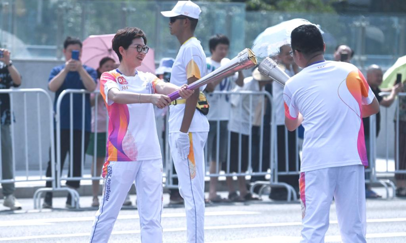 Torch bearers Tu Hongyan (L) and Yu Jianxin pass the flame during the torch relay of the 19th Asian Games in Shaoxing, east China's Zhejiang Province, Sept. 11, 2023. (Xinhua/Xu Yu)