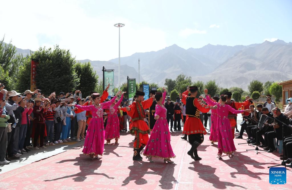 Members of a local song and dance ensemble dance to welcome tourists in front of the customer service center of Pamir Tourist Area in Taxkorgan Tajik Autonomous County, northwest China's Xinjiang Uygur Autonomous Region, Sept. 4, 2023. Taxkorgan, a border county home to no more than 50,000 residents, is renowned for its tourist attractions, and it has received more than 900,000 tourists in the first eight months of the year.(Photo: Xinhua)
