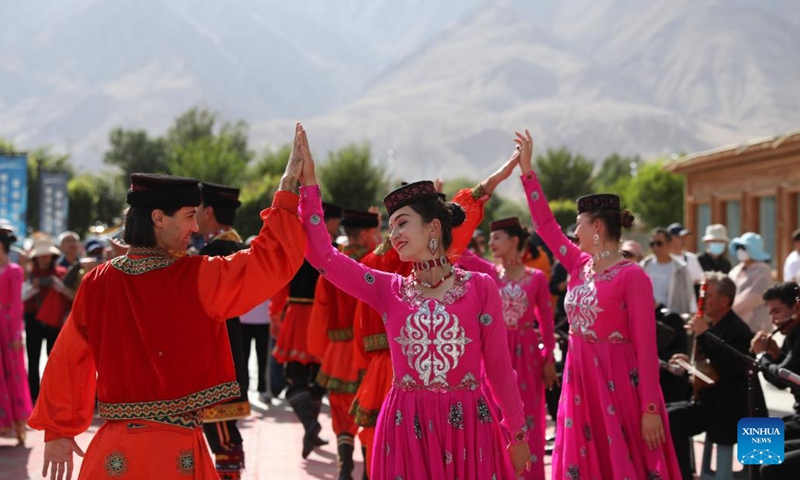 Members of a local song and dance ensemble dance to welcome tourists in front of the customer service center of Pamir Tourist Area in Taxkorgan Tajik Autonomous County, northwest China's Xinjiang Uygur Autonomous Region, Sept. 4, 2023. Taxkorgan, a border county home to no more than 50,000 residents, is renowned for its tourist attractions, and it has received more than 900,000 tourists in the first eight months of the year.(Photo: Xinhua)