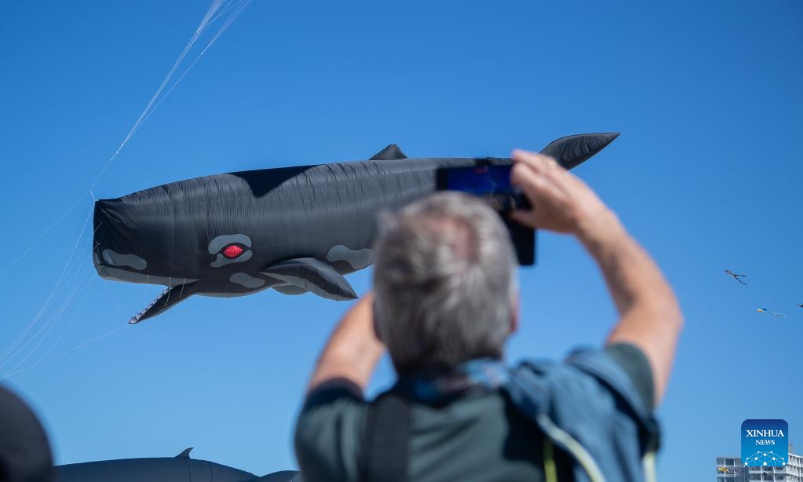 A man takes photos as kites fly above Bondi Beach in Sydney, Australia, Sept. 10, 2023. Kite lovers flocked to Sydney's famous Bondi Beach on Sunday for Australia's annual kite festival, the Festival of the Winds. (Photo by Hu Jingchen/Xinhua)