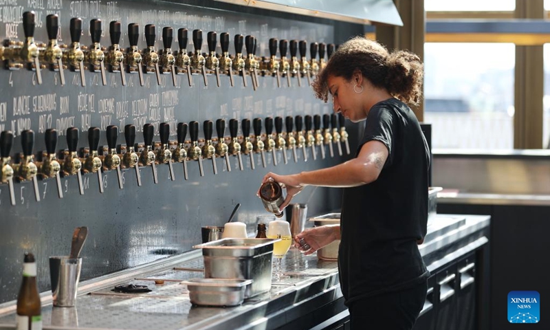 A staff member serves beer at a rooftop bar of the Belgian Beer World in Brussels, Belgium, Sept. 9, 2023. The Belgian Beer World, which showcases Belgium's brewing tradition through a series of interactive exhibits and workshops, opened its doors to the public here on Saturday. Photo: Xinhua