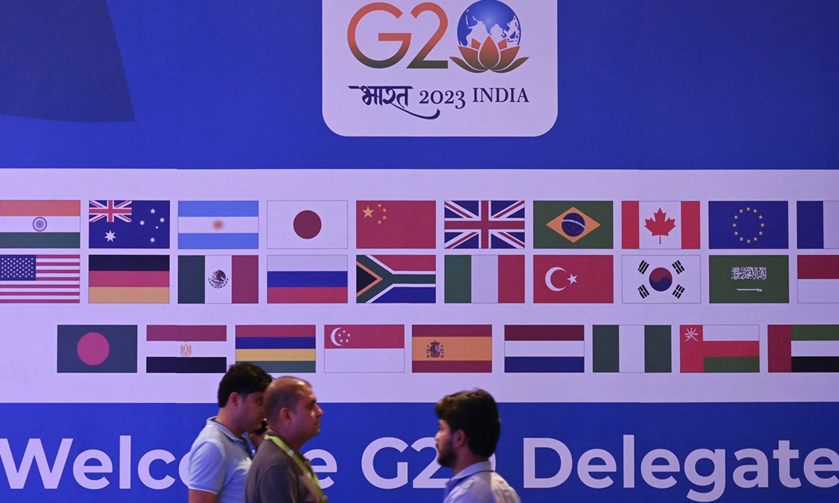 People walk past a banner with flags of countries participating in G20 summit at the International Media Center at G20 venue on the eve of the two-day G20 summit in New Delhi on September 8, 2023. Photo: AFP