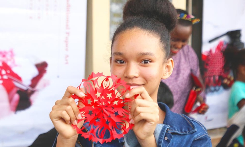 A girl shows her Chinese paper-cut work at a Chinese cultural exhibition in Kigali, Rwanda, Sept. 23, 2023. Hundreds of Rwandans and Chinese people living in Rwanda braved the afternoon bad weather to attend an action-packed Chinese cultural exhibition in Kigali, the capital of Rwanda, over the weekend. (Photo by Huang Wanqing/Xinhua)