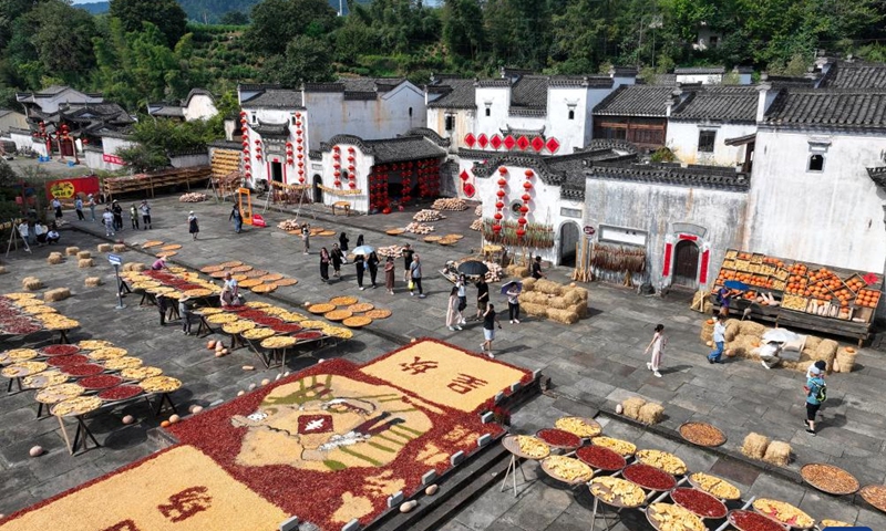 This aerial photo taken on Sept. 19, 2023 shows tourists viewing the dried crops at Chengkan Village in Huangshan City, east China's Anhui Province. Shaiqiu, or drying crops in autumn, is a rural tradition in China. Crops of different colors are placed to form various patterns which become attractions for tourists. (Photo by Fan Chengzhu/Xinhua)