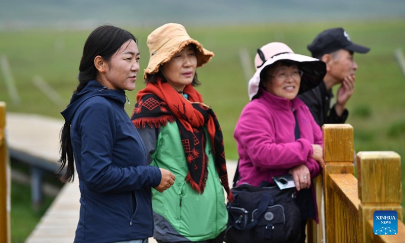 A staff member (1st L) briefs tourists on the situation of the wild animals and plants in the Gahai-Zecha National Nature Reserve in Gannan Tibetan Autonomous Prefecture, northwest China's Gansu Province, on July 7, 2023.（Photo: Xinhua)
