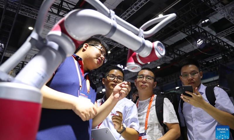 A staff member (L) talks with visitors beside a robot during the 23rd China International Industry Fair (CIIF) in east China's Shanghai, Sept. 19, 2023. The 23rd CIIF kicked off here on Tuesday, with the theme of Digital Economy & Industrial Decarbonization.(Photo: Xinhua)