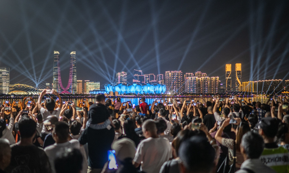 People gather at the promenade of Qiantang River to watch the light show of the Hangzhou Olympic Sports Centre Stadium (C), ahead of the 2022 Asian Games in Hangzhou in East China's Zhejiang Province on September 19, 2023. Photo: VCG