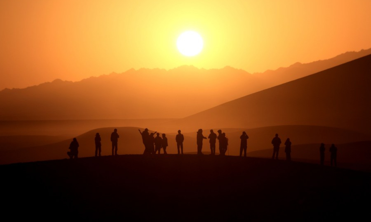 Tourists enjoy the sunrise view at the Mingsha Mountain and Crescent Spring scenic spot in Dunhuang, northwest China's Gansu province, Oct 2, 2023. Photo:Xinhua