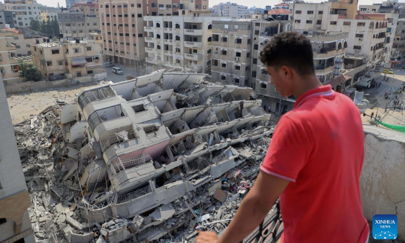 A man looks at destroyed buildings following an Israeli airstrike in Gaza City, October 8, 2023. Photo: Xinhua