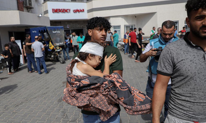 Un homme transporte un enfant blessé à l’hôpital après des frappes aériennes israéliennes dans la ville de Gaza, le 17 octobre 2023. Photo : Xinhua