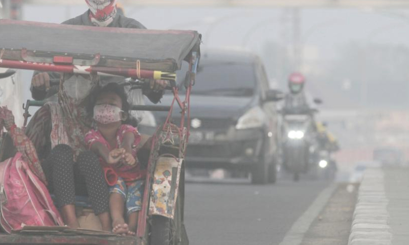 People wear face masks as they move across a bridge in peatland fire-induced smoke in Palembang, South Sumatra, Indonesia, Oct. 3, 2023. (Photo by M. Hatta/Xinhua)