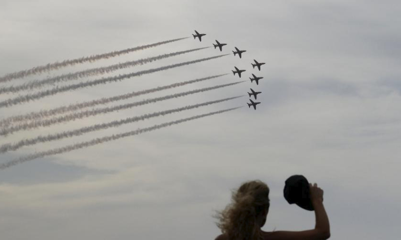A woman watches an aerobatic demonstration of the Malta International Airshow in Bugibba, Malta on Sept. 23, 2023. The Malta International Airshow is held on Saturday and Sunday, featuring aerobatic demonstrations. (Photo by Jonathan Borg/Xinhua)