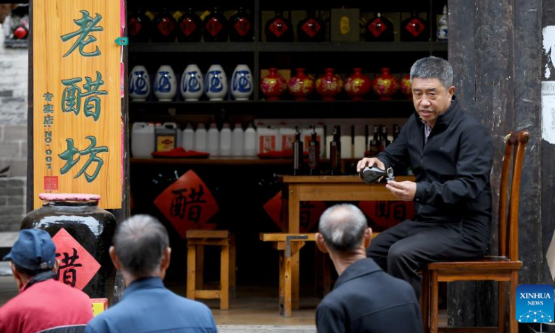 Zhang Hailong invites tourists to taste his vinegar products in the Qikou ancient town of Linxian County, north China's Shanxi Province, Sept. 26, 2023. Zhang once worked as a truck driver and opened a vinegar shop in the Qikou ancient town in 2018. Qikou, an ancient riverine town along the Yellow River, was an important trade ferry in history. However, with the development of land transportation, the Qikou ancient town declined in terms of trade volume, leaving many of its historical buildings in disrepair. In recent years, local authorities have carried out protection and restoration of historical buildings and ancient dwellings in the Qikou ancient town. At the same time, the integrated development of culture and tourism is also promoted. Today the ancient town has become a popular tourist attraction. More than 5,000 people out of a population of about 30,000 in the town are engaged in the tourism industry.(Photo:Xinhua)