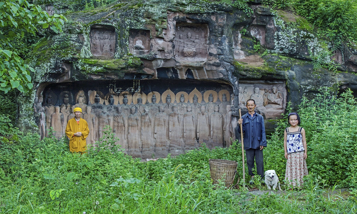 A local guardian (middle) in Niujiaozhai, Southwest China's Sichuan Province, and his granddaughter (right) pose for a photo while a Buddhist monk stands nearby. Photo: Courtesy of Yuan Rongsun