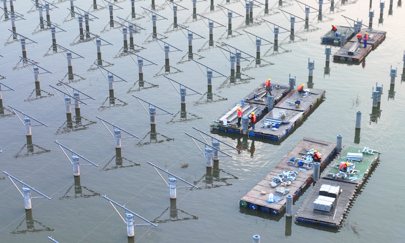 Workers install photovoltaic (PV) panels on pillars of a fishing-light complementary PV power station in Dunshang town, East China's Jiangsu Province on October 22, 2023. The project combines solar power generation and aquaculture, and it will have a total installed capacity of 276 megawatts, covering an area of 8,500 mu (567 hectares). The station will go into operation in September 2024, with annual power generation of 460 million kilowatt-hours. Photo: VCG