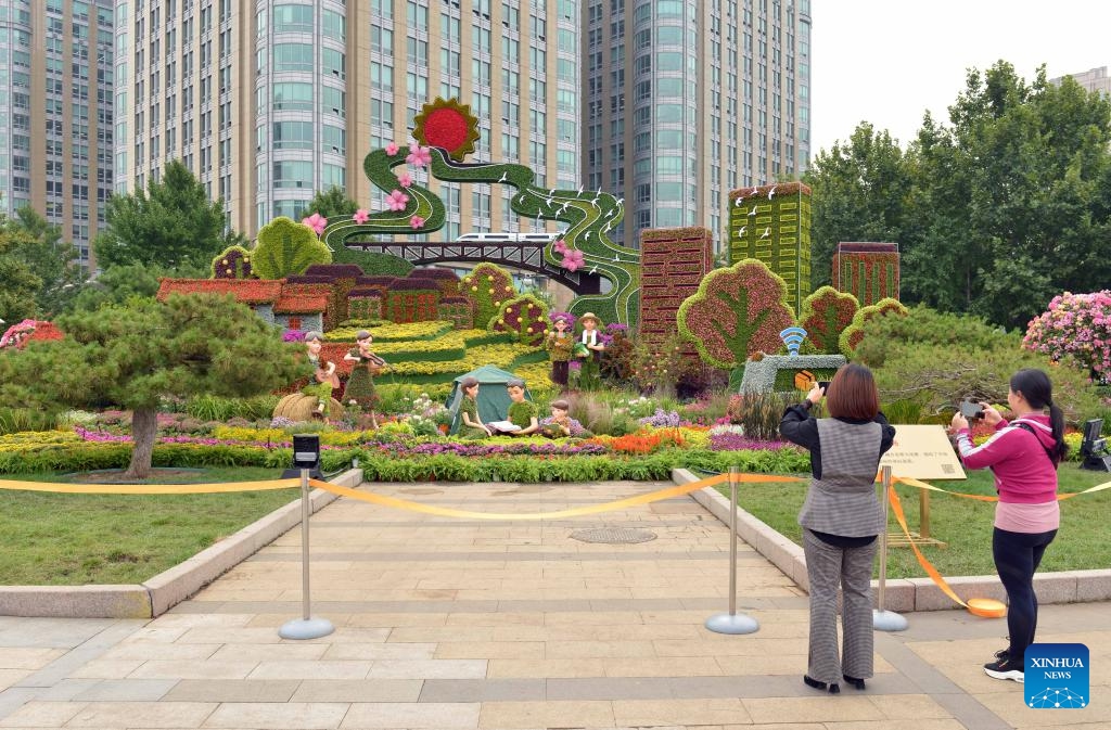 People take photos of a floral decoration at Dongdan area in Beijing, capital of China, Sept. 25, 2023. As the Mid-Autumn Festival and National Day holidays approach, an 18-meter-high flower basket at Tian'anmen Square and other floral displays along the Chang'an Avenue debuted in Beijing, attracting people to visit.(Photo: Xinhua)