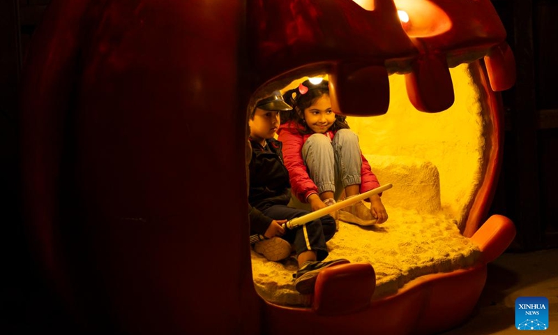 Children pose for photos in a Jack-o-lantern during the 2023 Pumpkins After Dark event in Milton, Ontario, Canada, on Sept. 23, 2023. Featuring over 10,000 hand-carved pumpkins, the annual Canada's outdoor Halloween event is held here from Sept. 23 to Oct. 31. (Photo by Zou Zheng/Xinhua)