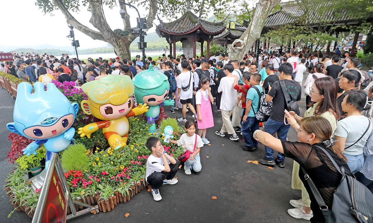 Tourists pose in front of the mascot statues of the Hangzhou Asian Games in West Lake Scenic Area in Zhejiang Province on September 30, 2023. Photo: VCG