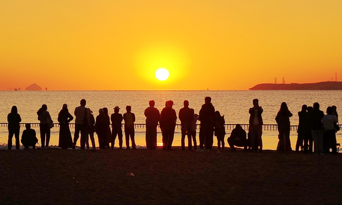 Tourists watch the sunrise over the sea in Qingdao, East China's Shandong Province on October 1, 2023. Photo: VCG