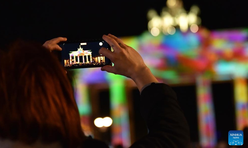 A visitor takes photos of the illuminated Brandenburg Gate during the 2023 Festival of Lights in Berlin, Germany, Oct. 6, 2023. Berlin on Friday turned into a city of light art with the opening of the 2023 Festival of Lights, which will last until Oct. 15. (Xinhua/Ren Pengfei)