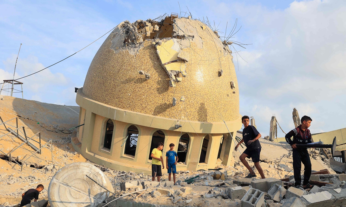 Children walk on the ruins of a mosque destroyed in Israeli airstrikes in Khan Yunis, southern Gaza Strip, on October 8, 2023. Fighting between Israeli forces and the Palestinian militant group Hamas raged on October 8, with hundreds killed on both sides after a surprise attack on Israel prompted Prime Minister Benjamin Netanyahu to warn they were 