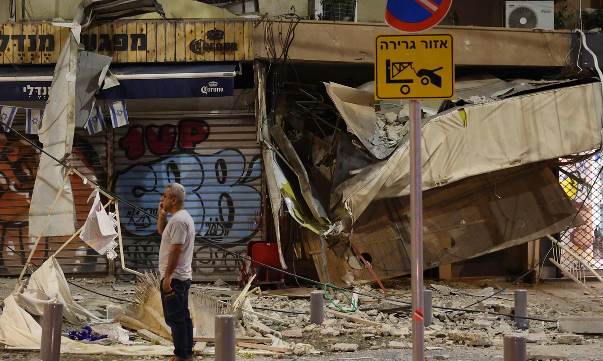 A man stands in front of a damaged shop in Tel Aviv, after it was hit by a rocket fired by Palestinian militants from the Gaza Strip on October 7, 2023. Photo: VCG
