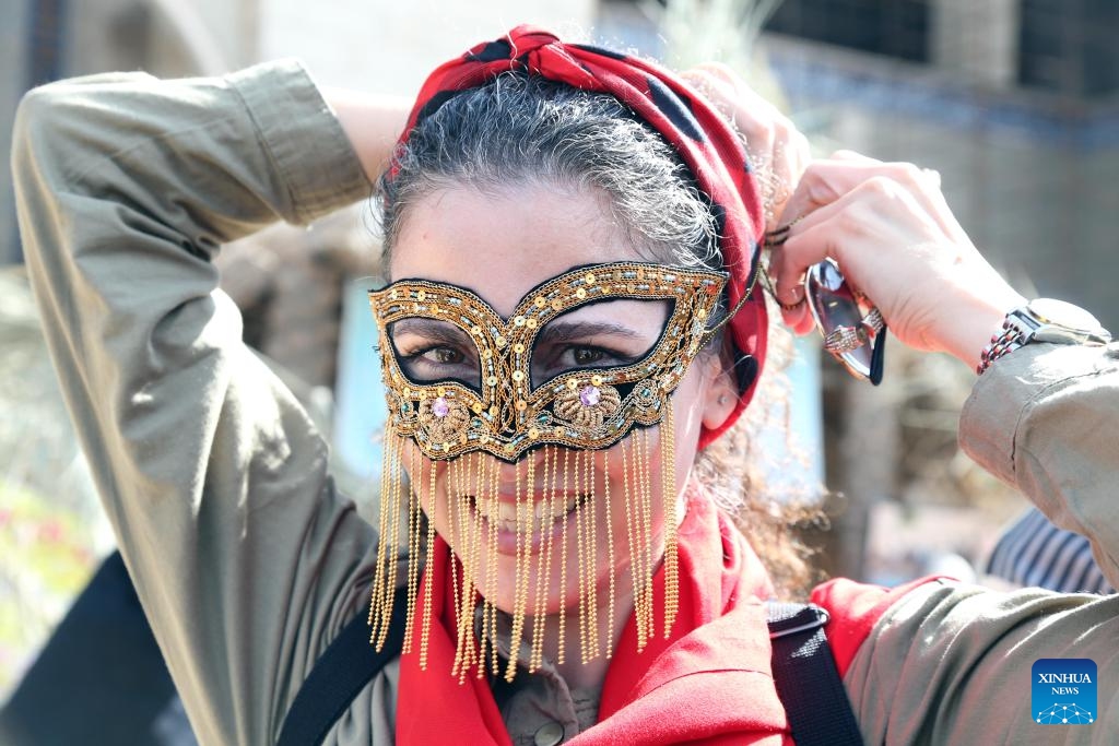 A woman tries a mask during a traditional cultural event in Tehran, Iran, Oct. 10, 2023.(Photo: Xinhua)