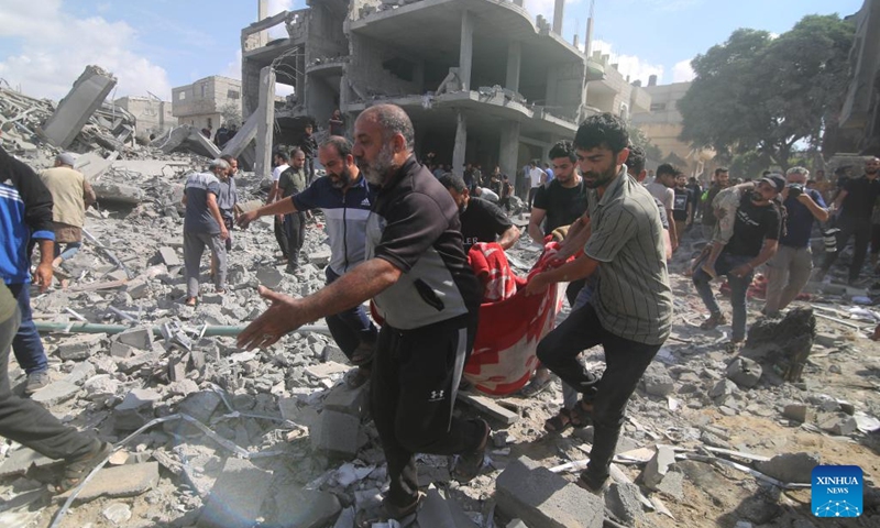 People remove a victim from a building destroyed in Israeli airstrikes in the southern Gaza Strip city of Rafah, on Oct. 17, 2023. The number of Palestinian deaths caused by Israeli airstrikes in Gaza has risen to 3,000, according to the Gaza-based Health Ministry. The Israeli airstrikes were triggered by a large-scale Hamas attack on Israeli military targets and towns on Oct. 7, which has so far killed at least 1,300 people in Israel.(Photo: Xinhua)