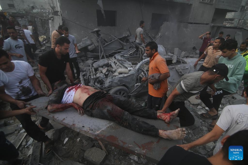 People remove a victim from a building destroyed in Israeli airstrikes in the southern Gaza Strip city of Rafah, on Oct. 17, 2023. The number of Palestinian deaths caused by Israeli airstrikes in Gaza has risen to 3,000, according to the Gaza-based Health Ministry. The Israeli airstrikes were triggered by a large-scale Hamas attack on Israeli military targets and towns on Oct. 7, which has so far killed at least 1,300 people in Israel.(Photo: Xinhua)