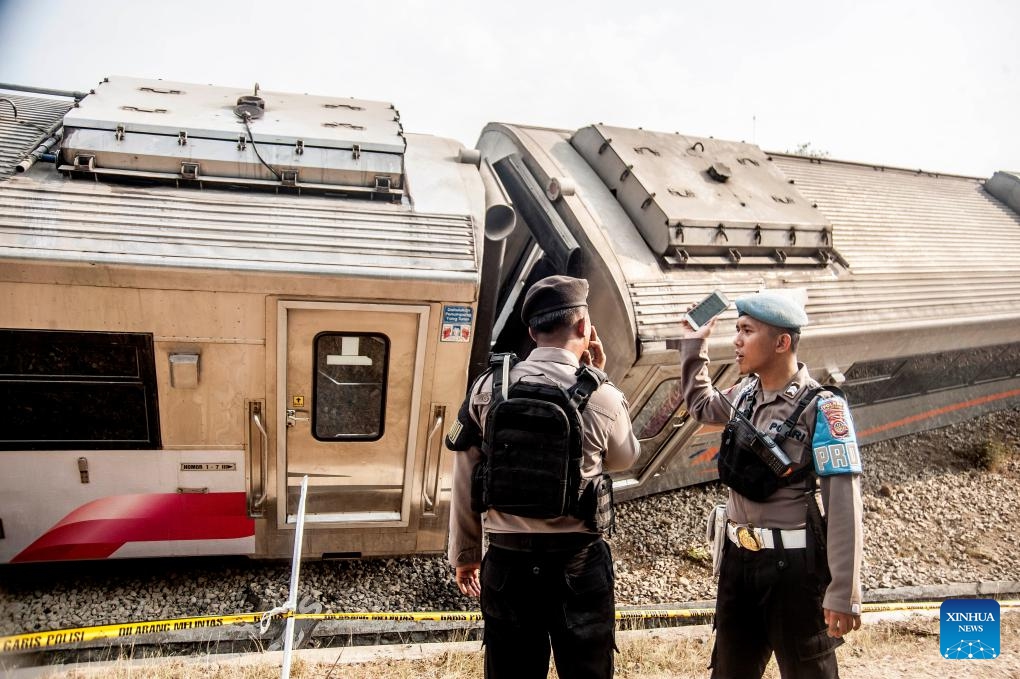 Police officers stand near a derailed train in Kulon Progo Regency, Yogyakarta, Indonesia, Oct. 17, 2023. A total of 32 people were injured in a train accident in Indonesia's Special Region of Yogyakarta on Tuesday, a rescuer said.(Photo: Xinhua)