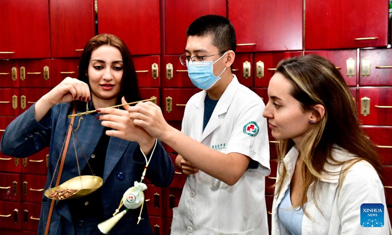 An Iranian student (1st L) from the College of International Exchange of the Shandong University of Science and Technology learns to weigh materials of traditional Chinese medicine at a traditional Chinese medicine hospital of the Xihai'an (West Coast) New Area in Qingdao, east China's Shandong Province, Oct. 18, 2023.(Photo: Xinhua)