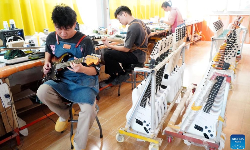 Staff members tune guitars at Tangwu Town of Changle County, east China's Shandong Province, Oct. 17, 2023. Tangwu Town, a town boasting musical instrument production, possesses 108 musical instrument manufacturing and musical instrument accessory processing enterprises, employing over 5000 people. They produce 2 million musical instruments and 5 million instrument accessories annually, generating a main business revenue of 1 billion yuan (about 140 million U.S. dollars).(Photo: Xinhua)