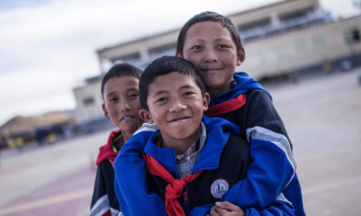 Three students pose in front of camera at the Sinopec Primary School on October 13, 2023. Photo: Shan Jie/GT