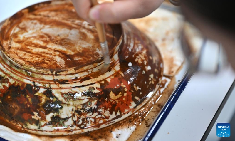 An archaeologist clears up a piece of cultural relic unearthed from ancient shipwrecks discovered in the South China Sea, Oct. 10, 2023. (Photo: Xinhua)