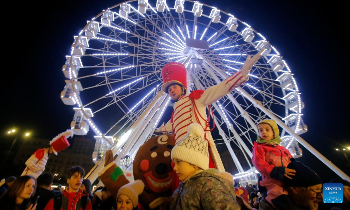 An entertainer poses with people visiting the Bucharest Christmas Market at the Constitution Square in Bucharest, Romania, Nov 30, 2023. Photo:Xinhua