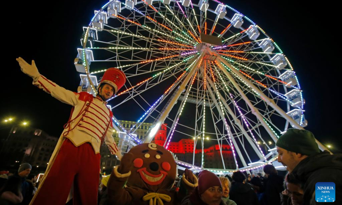 An entertainer poses with people visiting the Bucharest Christmas Market at the Constitution Square in Bucharest, Romania, Nov 30, 2023. Photo:Xinhua