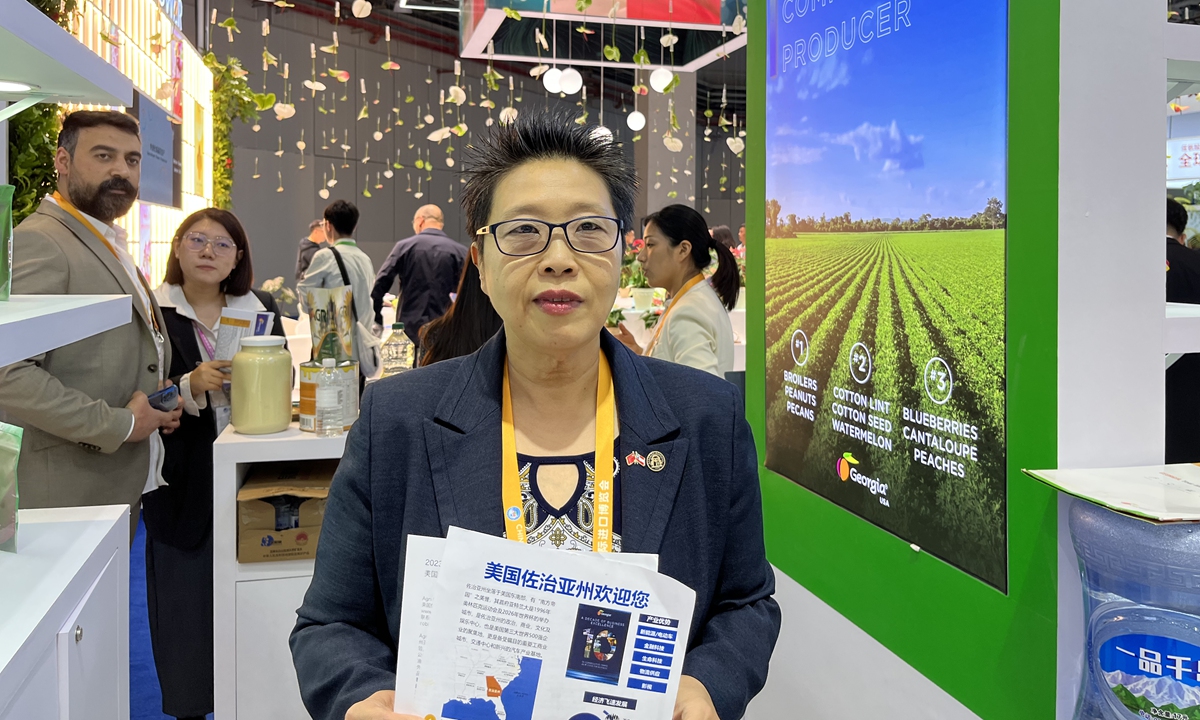 A trade official from Georgia poses for a photo at the state's booth with a brochure at the sixth CIIE on November 6, 2023. Photo: Chu Daye/GT