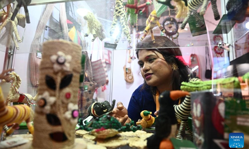 Tahera Toma, Nurus Safa's wife, arranges products at their booth during the 6th China International Import Expo (CIIE) in east China's Shanghai, Nov. 7, 2023. In 2018, Nurus Safa, founder of Dada Bangla Limited, participated in the expo for the first time, and his special products such as jute carpets, baskets and bags went popular at the time. During the past years, Safa's business has grown bigger and brought thousands of job opportunities to Bangladeshi families.(Photo: Xinhua)