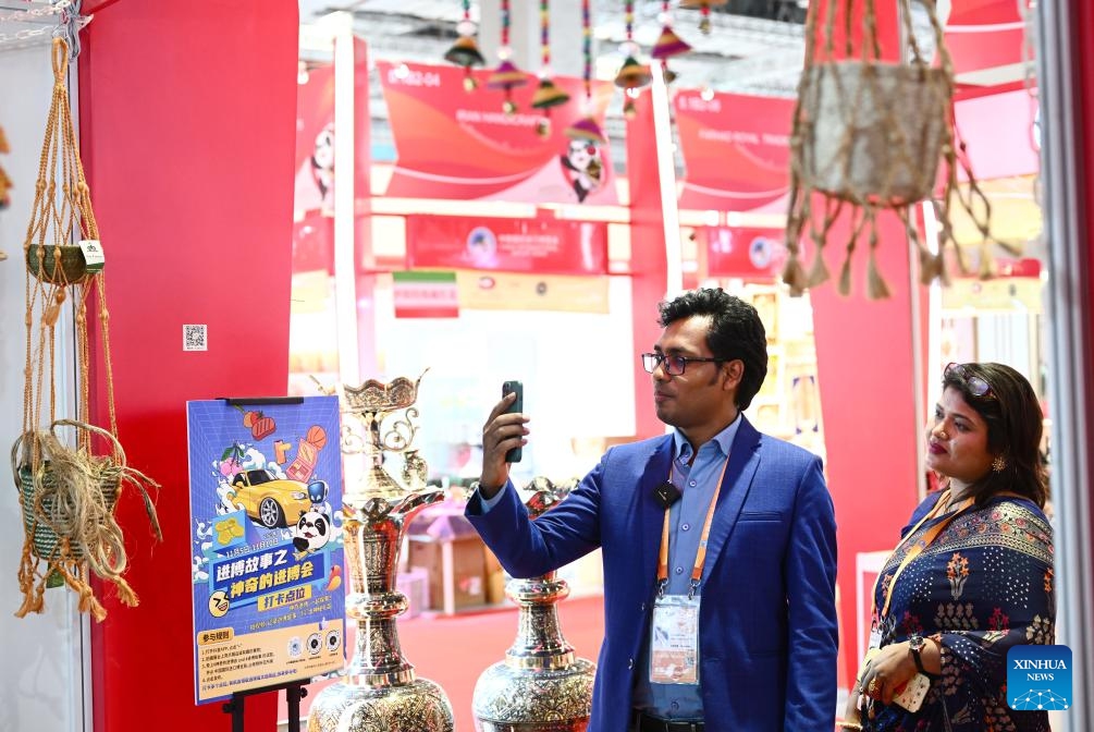 Nurus Safa and his wife Tahera Toma have a video call with Bangladeshi employees during the 6th China International Import Expo (CIIE) in east China's Shanghai, Nov. 7, 2023. In 2018, Nurus Safa, founder of Dada Bangla Limited, participated in the expo for the first time, and his special products such as jute carpets, baskets and bags went popular at the time.(Photo: Xinhua)