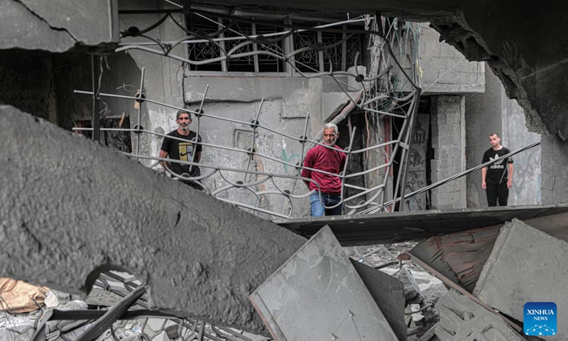People are seen among the rubble of buildings destroyed in an Israeli bombing at Bureij refugee camp in central Gaza Strip, on Nov. 13, 2023. The government media office in Gaza announced on Monday that the Palestinian death toll from Israeli attacks has risen to 11,240, while more than 28,000 others were injured.(Photo: Xinhua)
