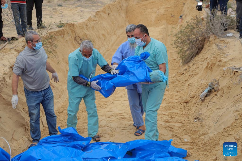 Palestinian workers transfer a body as they establish a mass grave for the victims inside and north of Gaza City, in the southern Gaza Strip city of Khan Younis, on Nov. 22, 2023. The Palestinian death toll in the Gaza Strip has risen to 14,532 since the outbreak of the Hamas-Israel conflict on Oct. 7, the Hamas-run government media office said Wednesday(Photo: Xinhua)