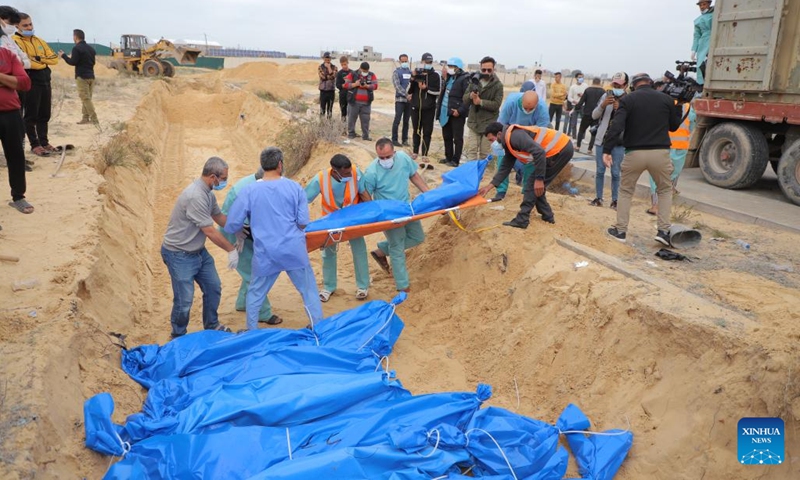 Palestinian workers transfer a body as they establish a mass grave for the victims inside and north of Gaza City, in the southern Gaza Strip city of Khan Younis, on Nov. 22, 2023. The Palestinian death toll in the Gaza Strip has risen to 14,532 since the outbreak of the Hamas-Israel conflict on Oct. 7, the Hamas-run government media office said Wednesday(Photo: Xinhua)