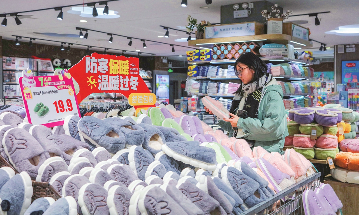 A customer checks out winter slippers at a supermarket in Guangshan county, Central China's Henan Province on November 26, 2023. Since early November, a large swath of the country has experienced cold spells, gusting winds, and plunging temperatures, as well as ice and snow, prompting people to buy down clothes, electric heaters and other necessities. 
Photo: VCG