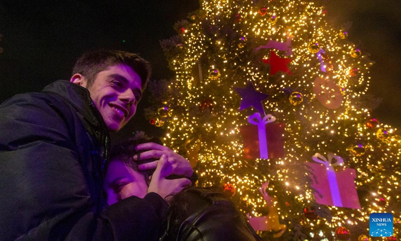 A couple hugs each other in front of an illuminated Christmas tree at Syntagma Square in Athens, Greece, on Nov. 23, 2023. The holiday season kicked off in Athens with a tree lighting ceremony on Thursday. (Photo: Xinhua)